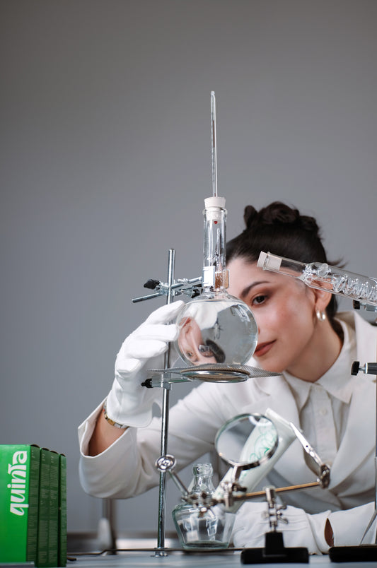 camila miranda, founder of quinta, formulating skincare by hand in a lab with glass beakers and small-batch tools
