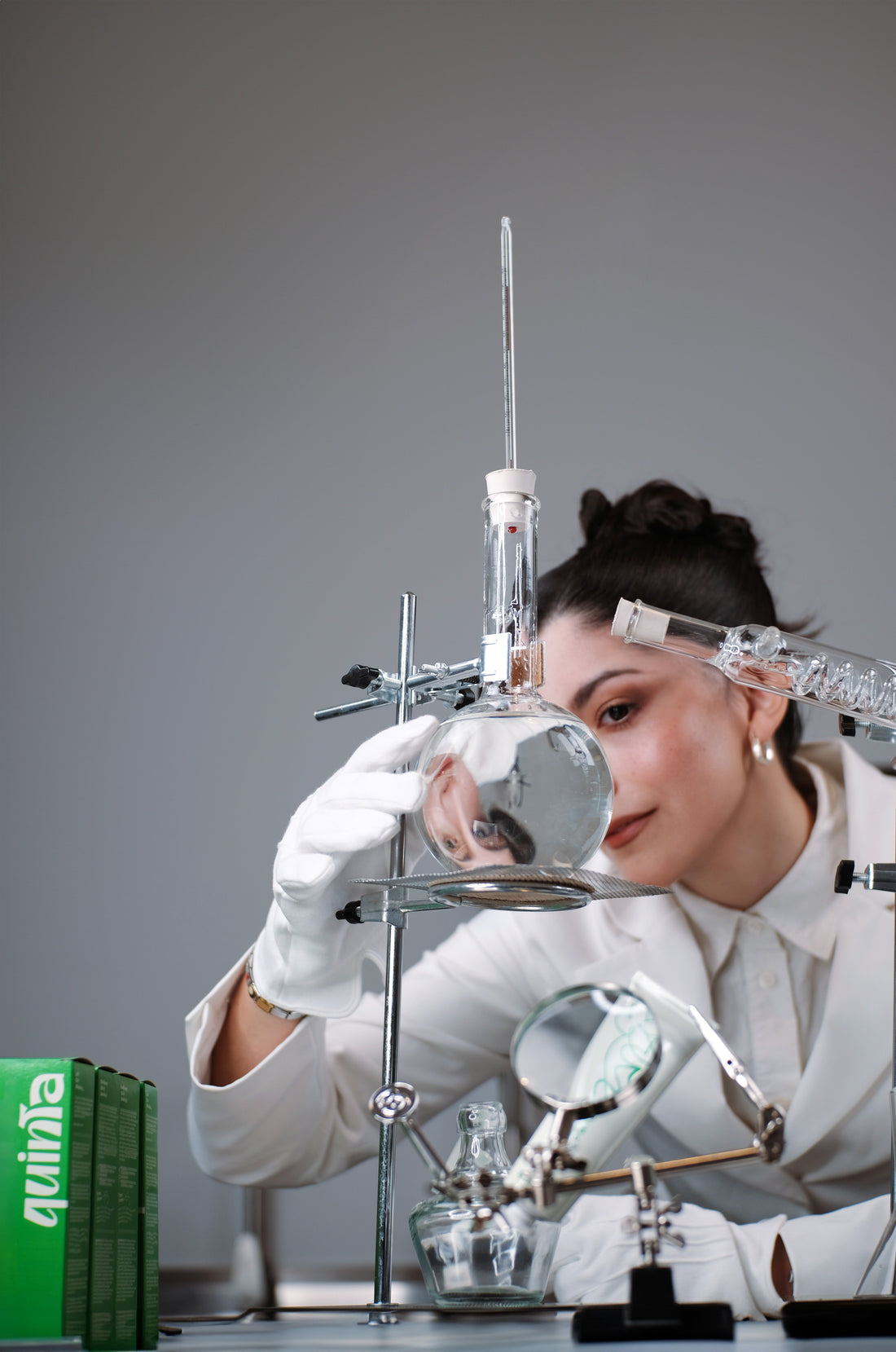 camila miranda, founder of quinta, formulating skincare by hand in a lab with glass beakers and small-batch tools