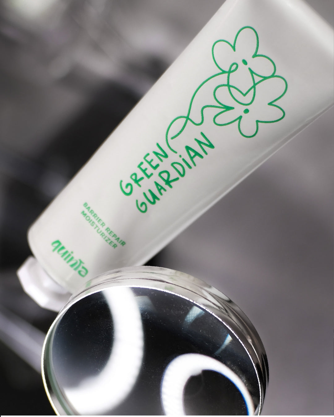 QUINTA Green Guardian Barrier Repair Moisturizer — frosted PCR aluminum tube with hand-drawn botanical branding, photographed with lab glassware. Petroleum-free, small-batch natural skincare.