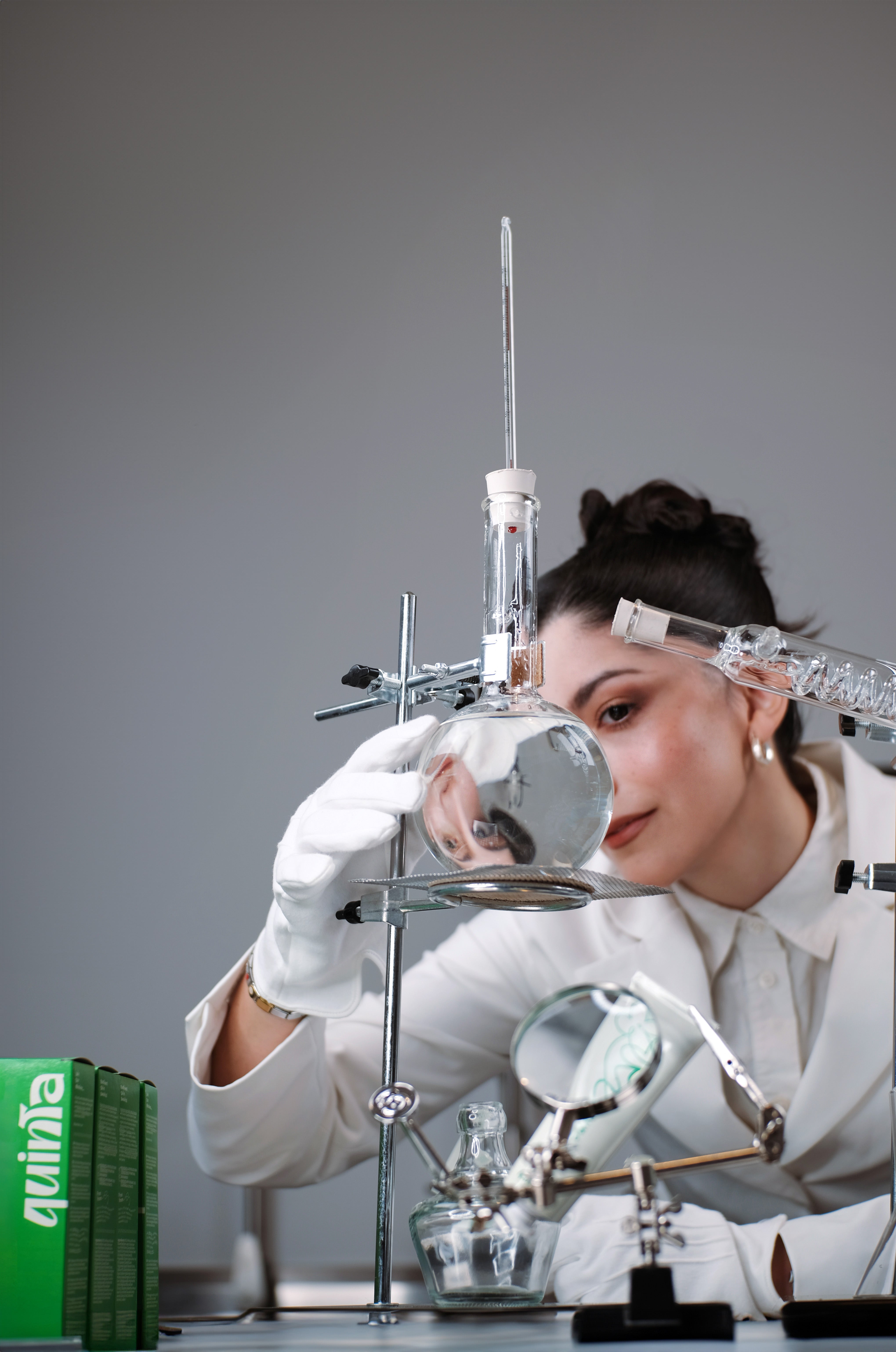 Person in a lab coat working with scientific equipment in a laboratory setting