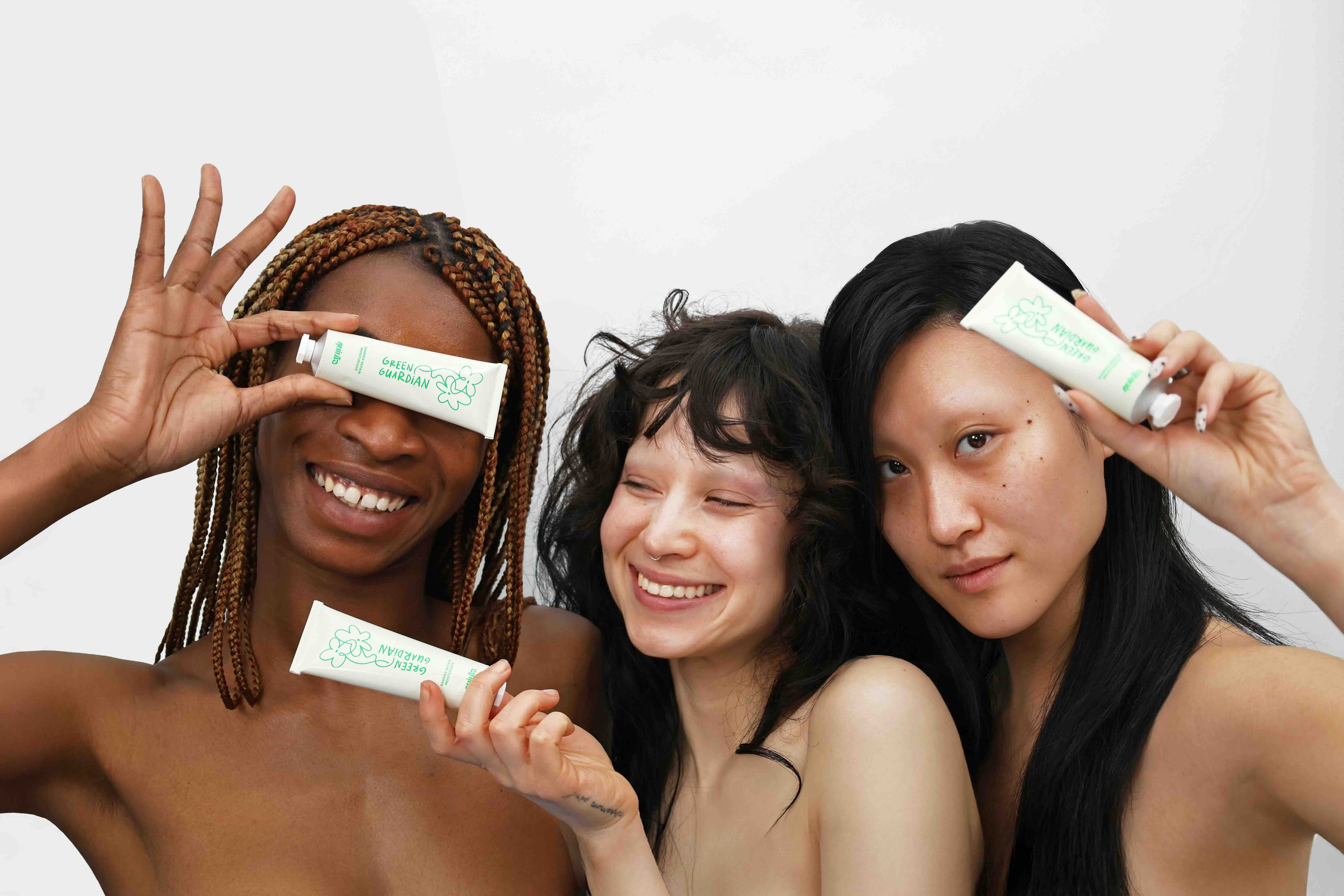 three diverse women playfully holding quinta green guardian moisturizer tubes sustainable skincare campaign