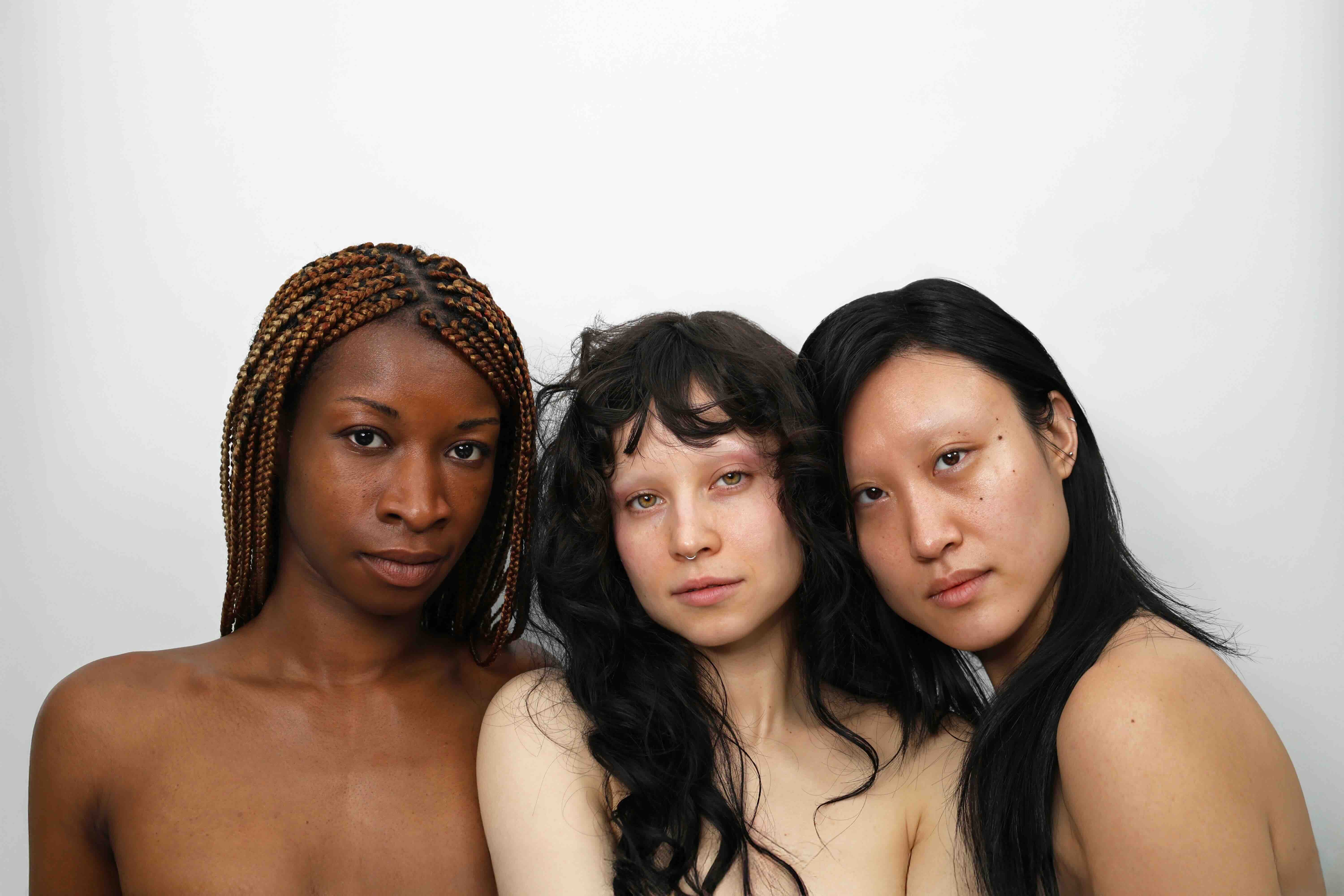 three women with different skin tones bare-faced standing together for quinta inclusive skincare campaign