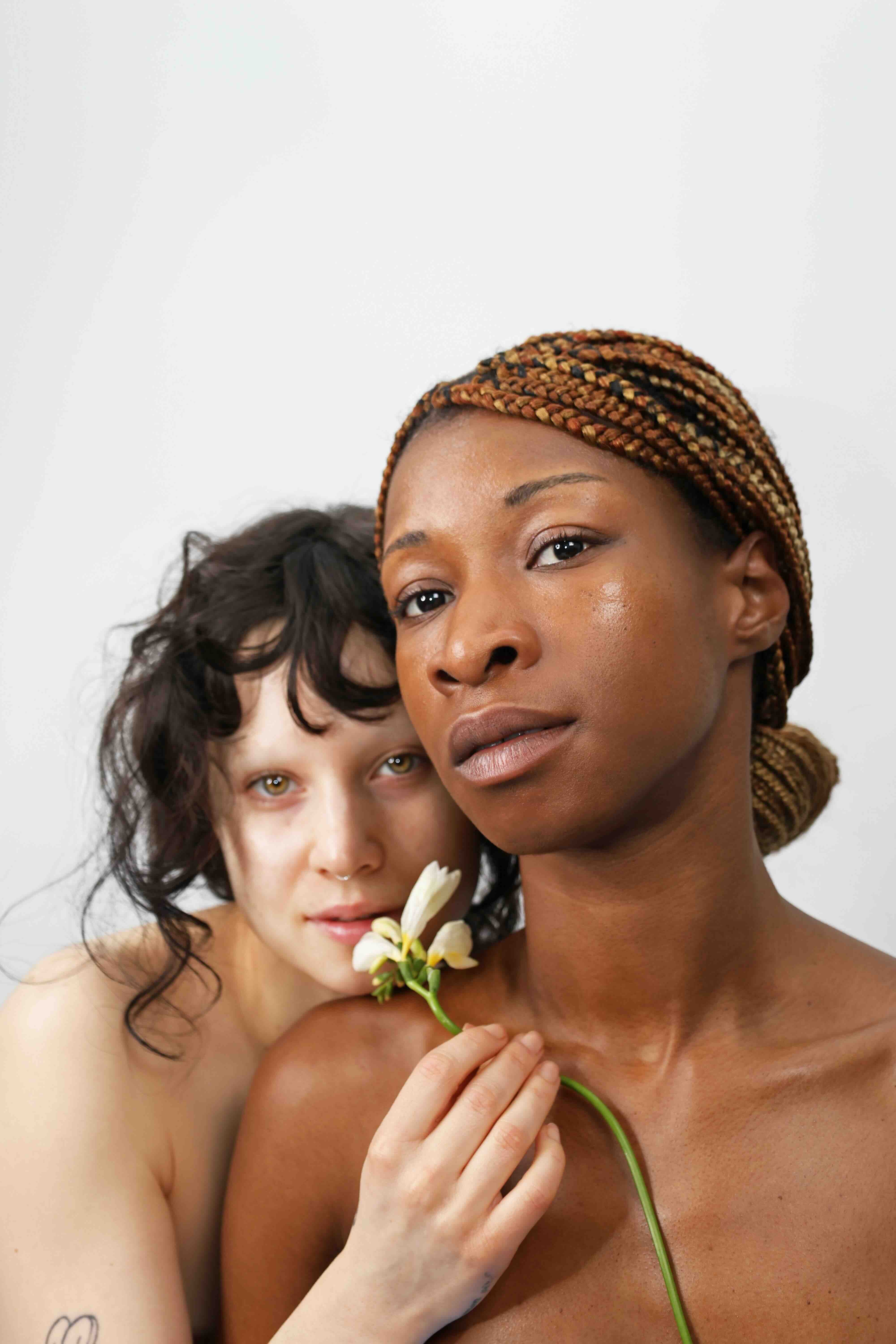 two women with different skin tones bare-faced holding flower for quinta natural skincare campaign